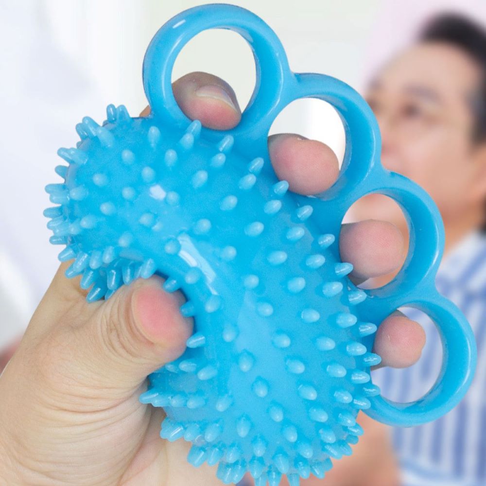 Person squeezing blue textured hand grip and finger exerciser ball with four-finger loop design NZ